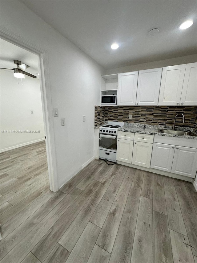 kitchen with white cabinetry, decorative backsplash, white appliances, light stone counters, and light wood-type flooring