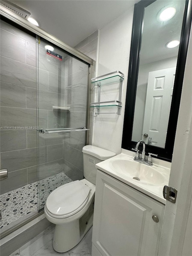 bathroom featuring vanity, a shower with shower door, and toilet