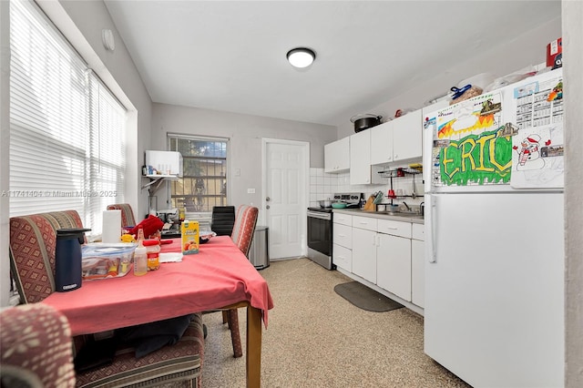 kitchen with sink, white cabinetry, tasteful backsplash, stainless steel electric stove, and white fridge