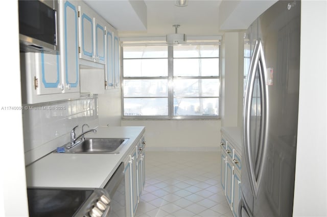 kitchen featuring sink, appliances with stainless steel finishes, tasteful backsplash, blue cabinets, and light tile patterned flooring