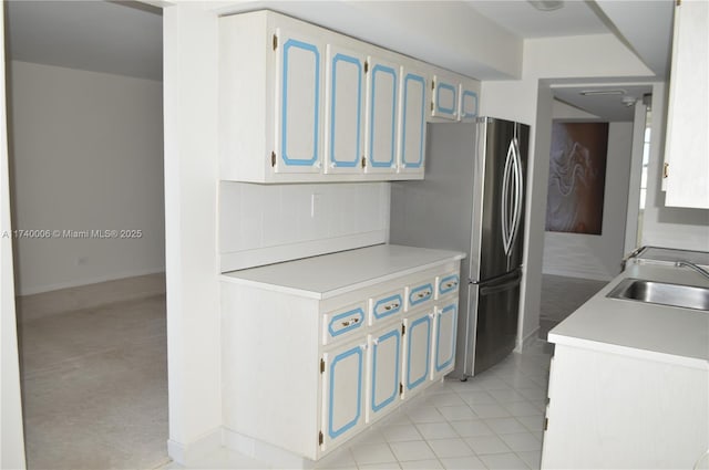kitchen featuring backsplash, a sink, freestanding refrigerator, and light countertops