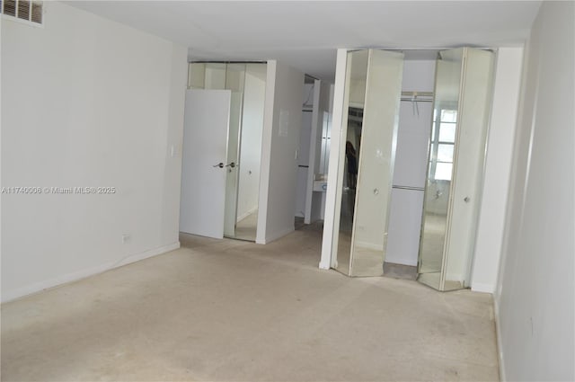 unfurnished bedroom with visible vents, light carpet, and multiple closets