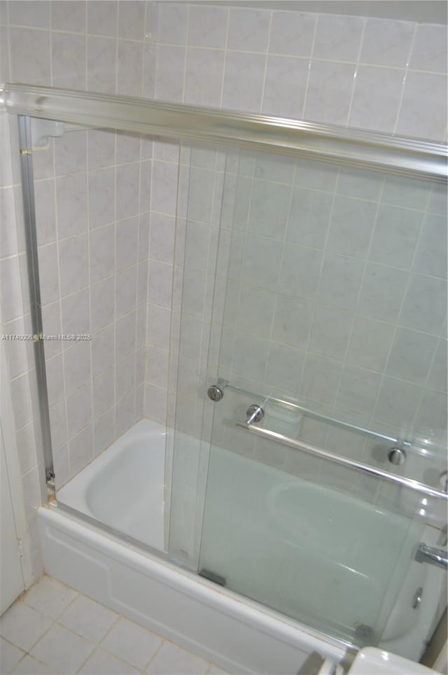 bathroom with tile patterned floors and bath / shower combo with glass door