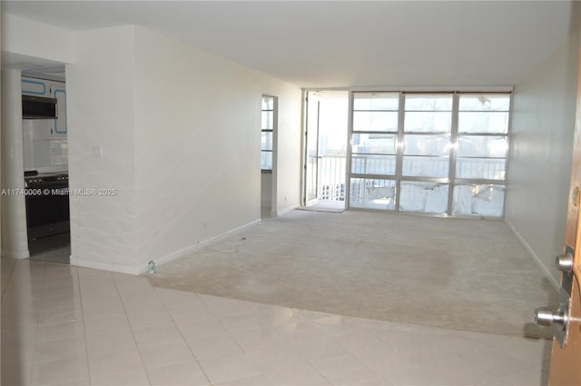spare room featuring tile patterned flooring, floor to ceiling windows, carpet, and baseboards