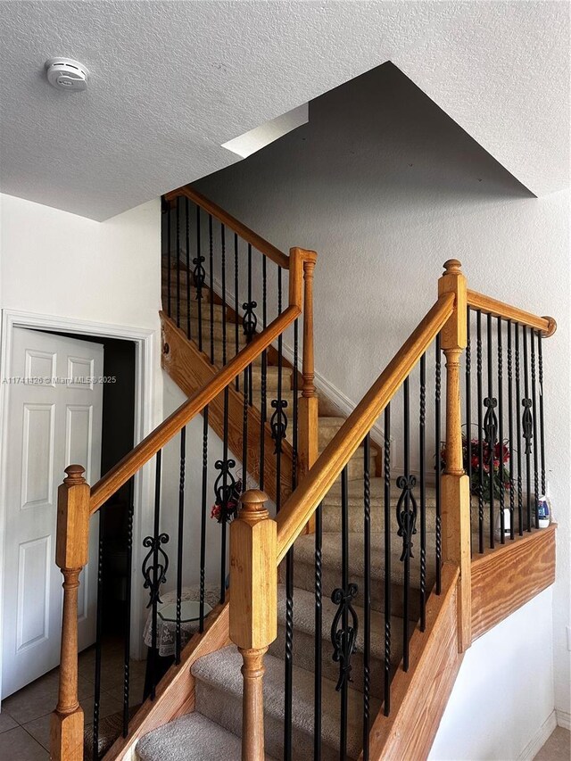 stairway featuring a textured ceiling