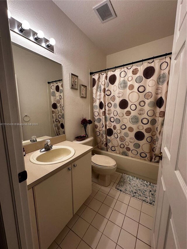 full bathroom with tile patterned flooring, vanity, shower / tub combo, toilet, and a textured ceiling