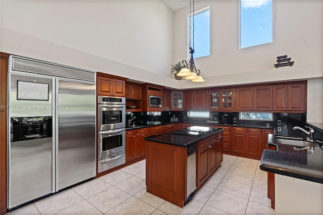 kitchen with sink, tasteful backsplash, built in appliances, light tile patterned floors, and a kitchen island