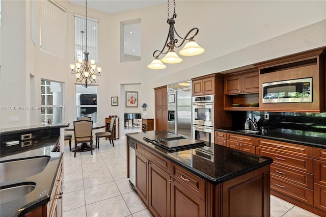 kitchen with pendant lighting, a center island, built in appliances, and dark stone counters