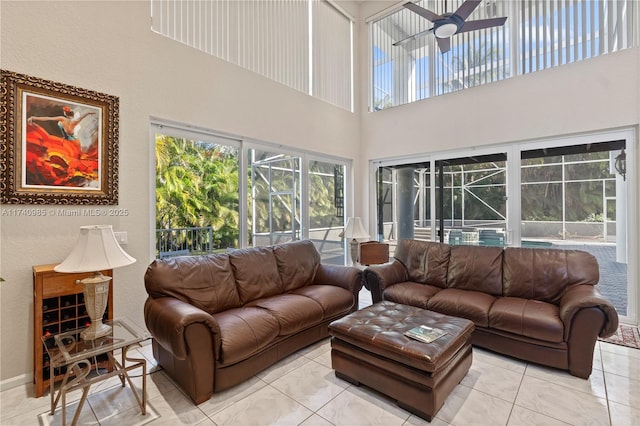 living room with light tile patterned flooring, ceiling fan, and a towering ceiling