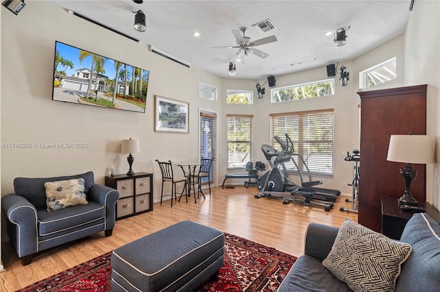 living room featuring ceiling fan, hardwood / wood-style floors, and a textured ceiling