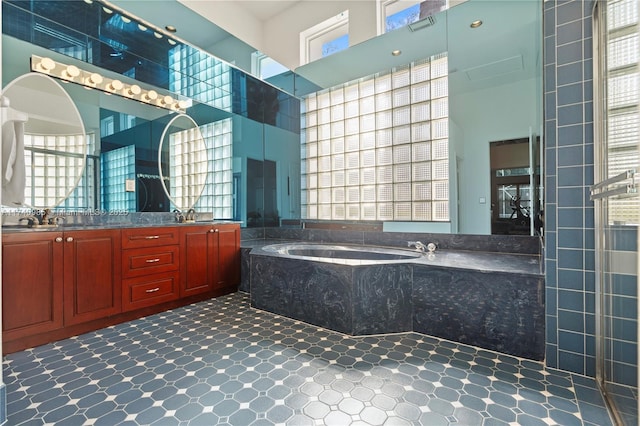 bathroom featuring vanity, a wealth of natural light, tiled bath, and a high ceiling