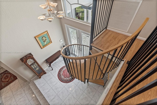 staircase with an inviting chandelier and tile patterned flooring