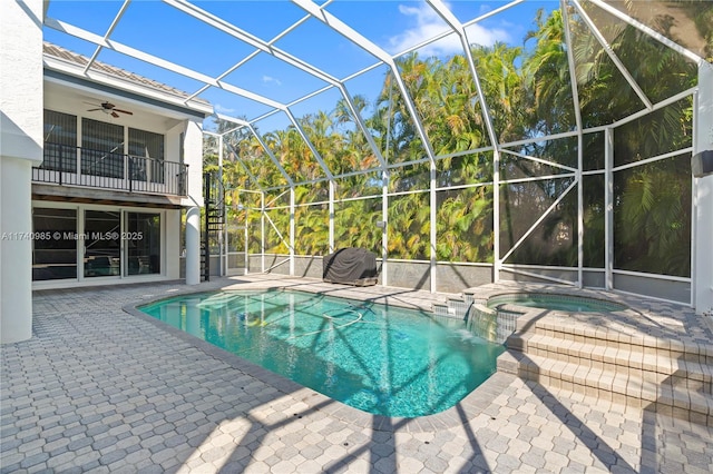 view of pool with an in ground hot tub, ceiling fan, a patio, and glass enclosure