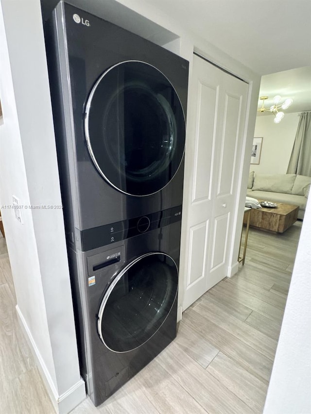 washroom with stacked washer and dryer and light wood-type flooring