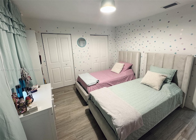 bedroom with hardwood / wood-style flooring and two closets