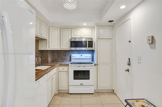 kitchen with sink, white appliances, light tile patterned floors, backsplash, and a tray ceiling