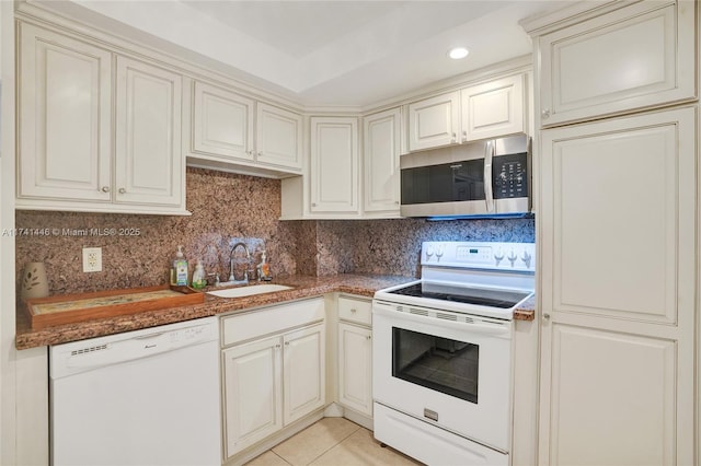 kitchen featuring sink, white appliances, light tile patterned floors, dark stone countertops, and tasteful backsplash