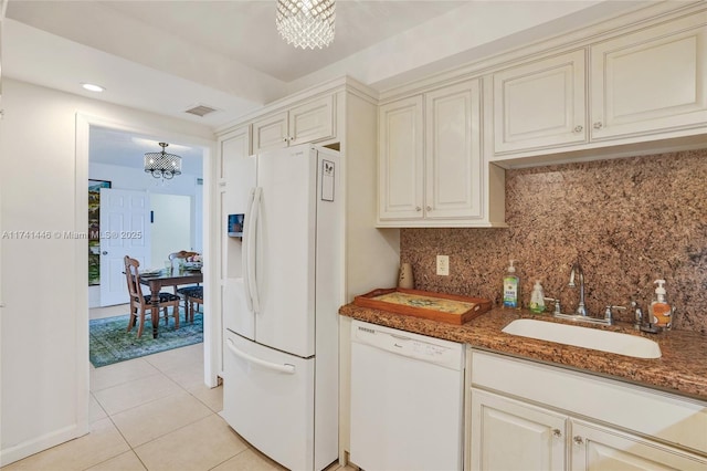 kitchen featuring sink, an inviting chandelier, white appliances, and dark stone counters