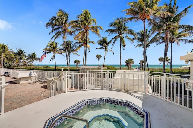 view of pool featuring an in ground hot tub, a water view, and a patio area