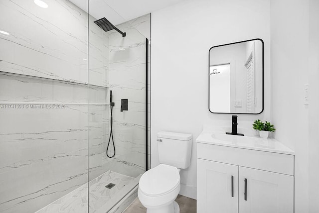 bathroom with a tile shower, vanity, and toilet