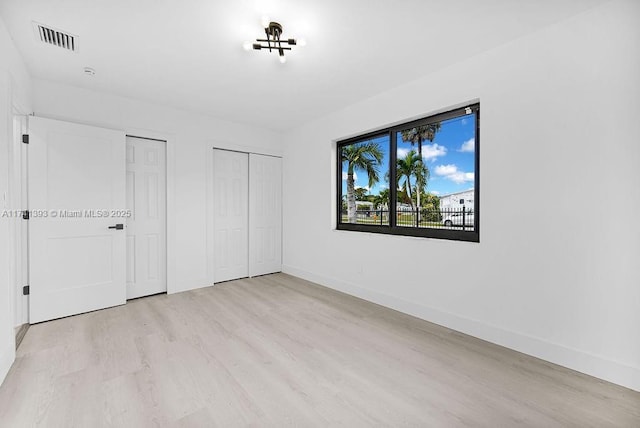 unfurnished bedroom with multiple closets and light wood-type flooring