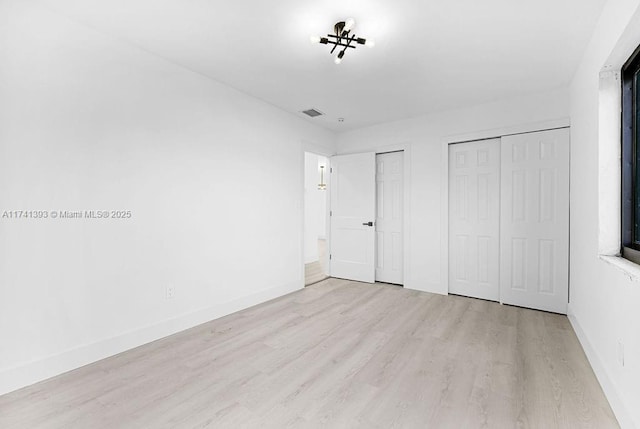 unfurnished bedroom featuring two closets and light hardwood / wood-style floors