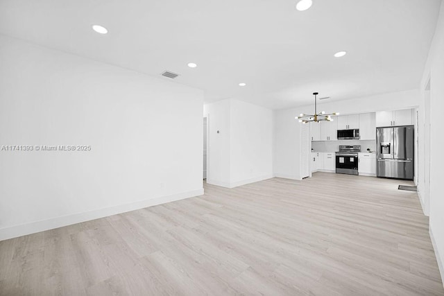 unfurnished living room with an inviting chandelier and light hardwood / wood-style flooring