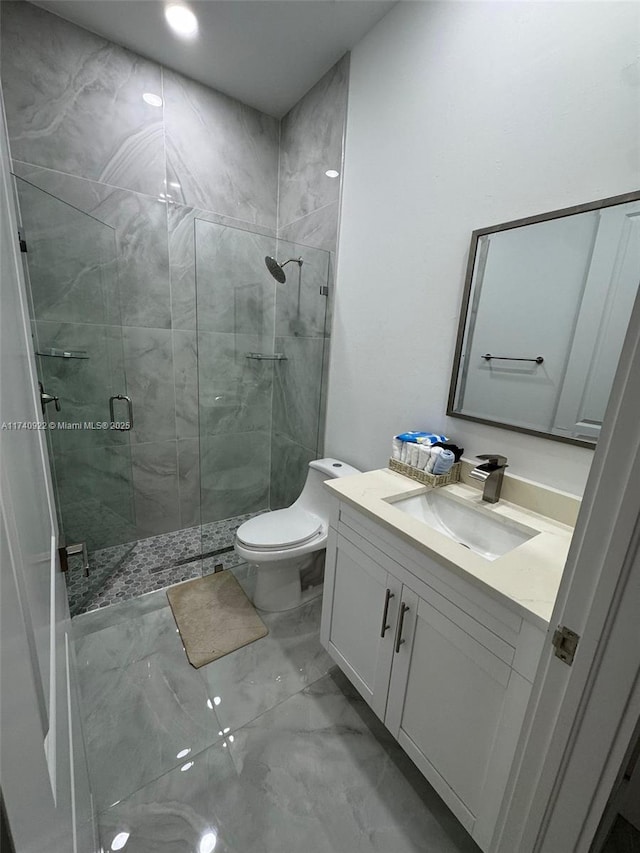 bathroom with vanity, a shower with door, and toilet