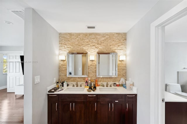 bathroom with tasteful backsplash, vanity, wood-type flooring, and toilet