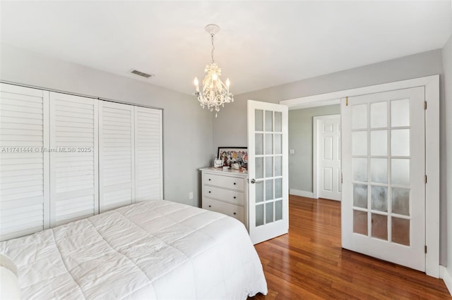 bedroom featuring an inviting chandelier, wood-type flooring, a closet, and french doors