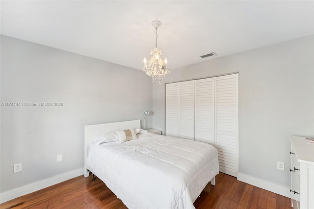 bedroom featuring dark hardwood / wood-style flooring, a chandelier, and a closet