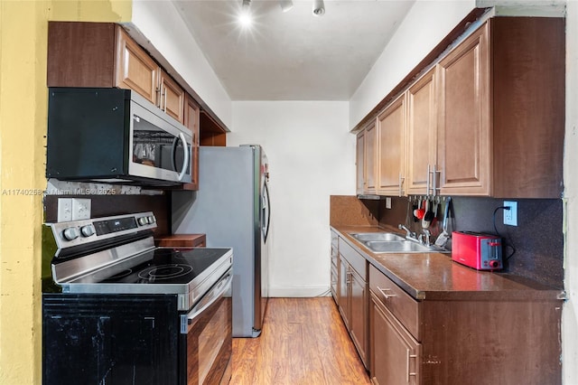 kitchen featuring stainless steel appliances, sink, and light wood-type flooring