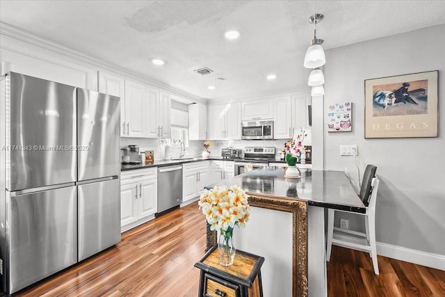 kitchen with white cabinetry, stainless steel appliances, kitchen peninsula, and hanging light fixtures