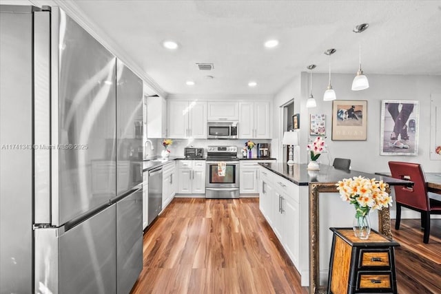 kitchen with pendant lighting, sink, light hardwood / wood-style flooring, appliances with stainless steel finishes, and white cabinets