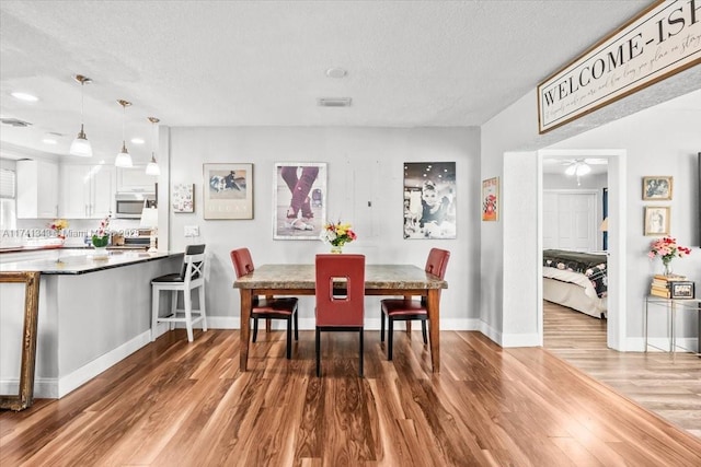 dining area with hardwood / wood-style flooring, ceiling fan, and a textured ceiling