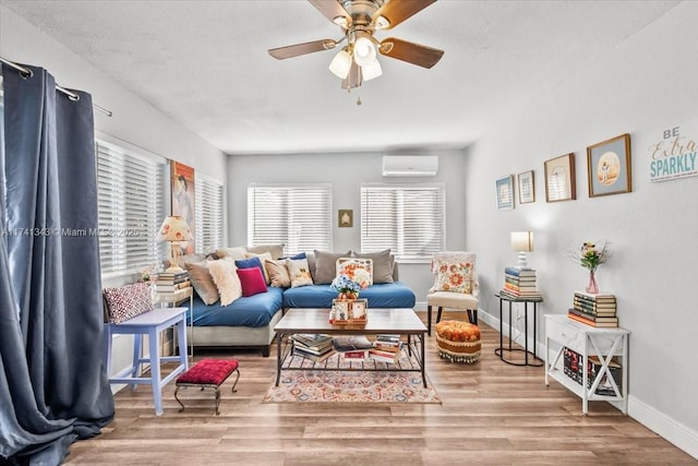 living room with ceiling fan, a textured ceiling, a wall unit AC, and light hardwood / wood-style flooring