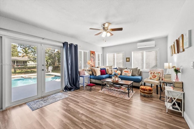 living room with an AC wall unit, plenty of natural light, hardwood / wood-style floors, and french doors