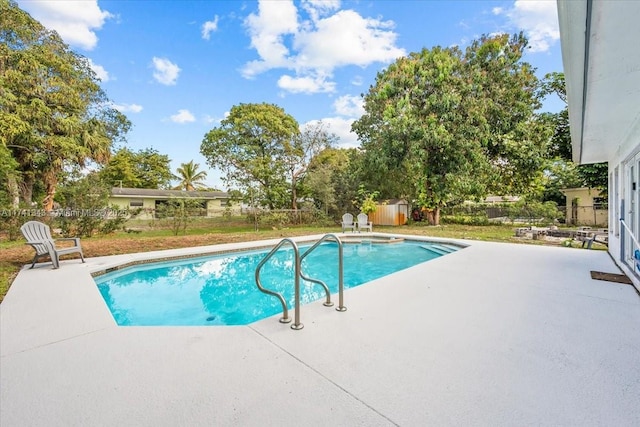 view of swimming pool featuring a patio area and a storage unit