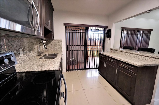 kitchen featuring tasteful backsplash, electric range oven, dark brown cabinetry, and sink