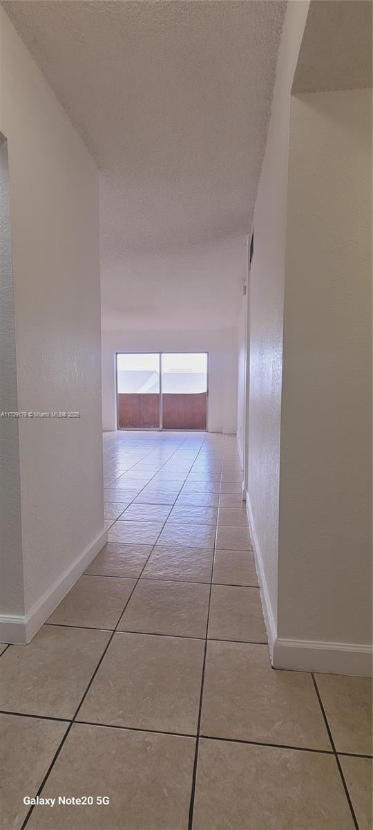 10900 SW 104th St Unit 316, Miami, FL 33176 - hallway with baseboards, light tile patterned flooring, and a textured ceiling
