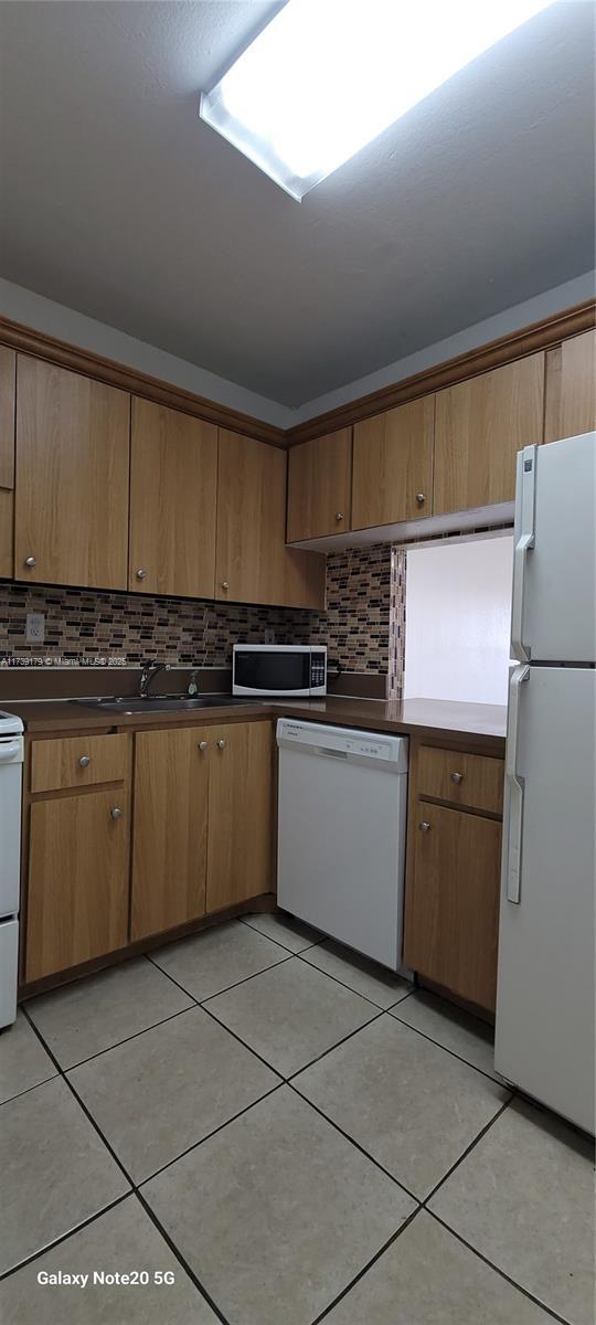 10900 SW 104th St Unit 316, Miami, FL 33176 - kitchen featuring decorative backsplash, white appliances, and light tile patterned floors