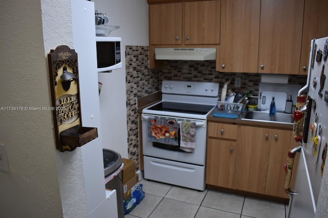 kitchen with white appliances, light tile patterned floors, sink, and backsplash