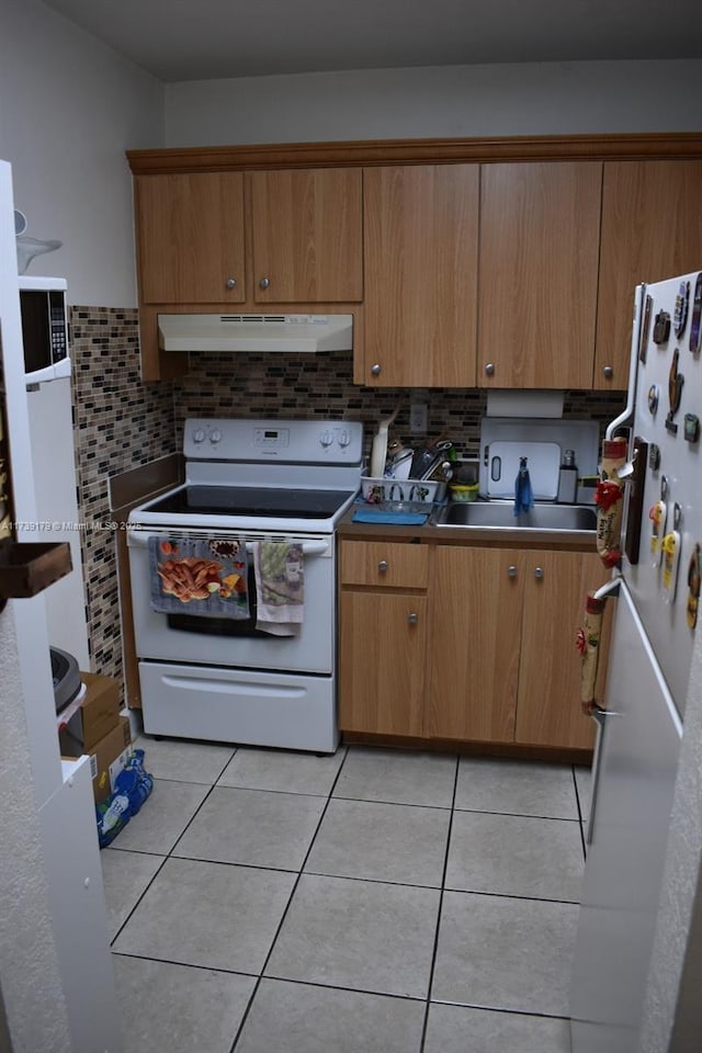 kitchen with light tile patterned floors, white appliances, range hood, and decorative backsplash