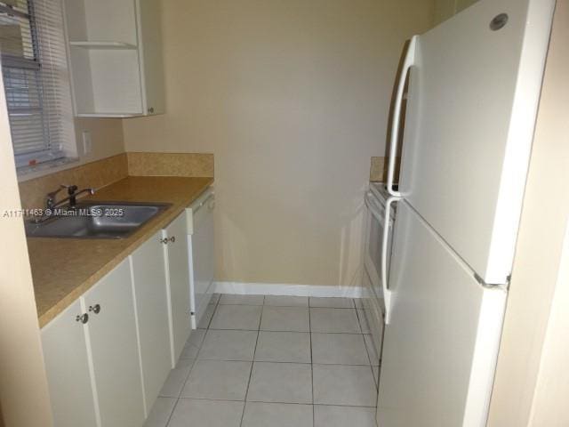 kitchen with white cabinetry, white appliances, sink, and light tile patterned floors