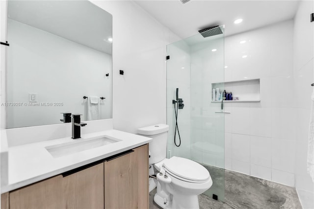 bathroom with tiled shower, vanity, and toilet