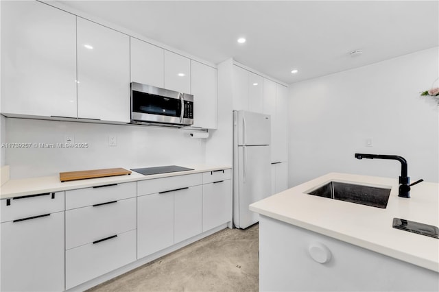 kitchen featuring black electric stovetop, sink, white cabinets, and white fridge