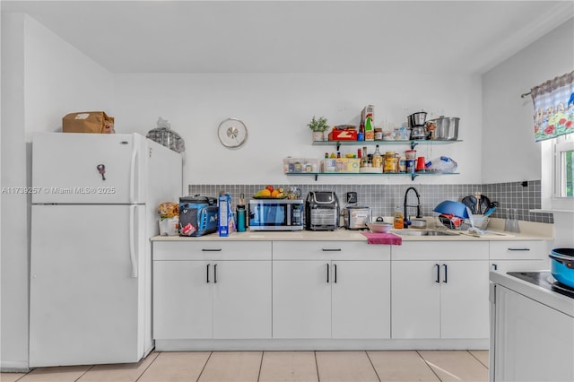 kitchen featuring white fridge, sink, white cabinets, and decorative backsplash