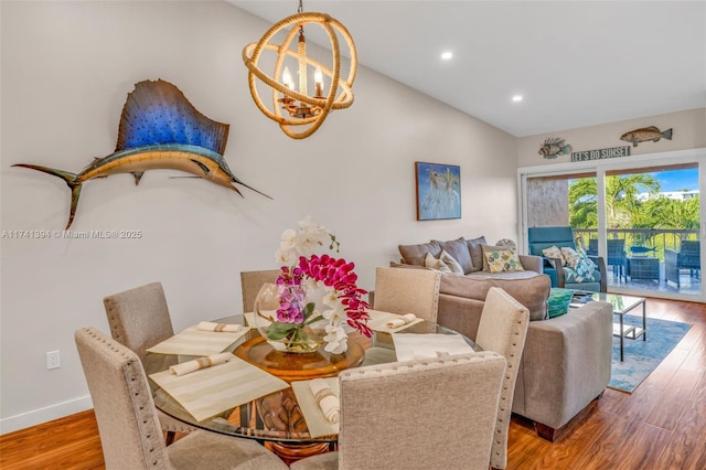 dining area featuring lofted ceiling, hardwood / wood-style floors, and a notable chandelier