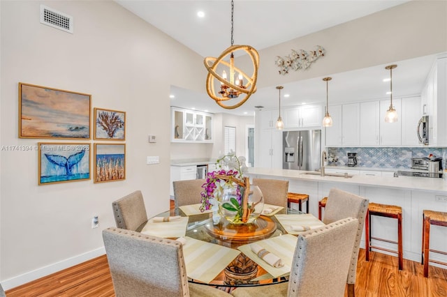 dining area with an inviting chandelier, light hardwood / wood-style floors, and sink