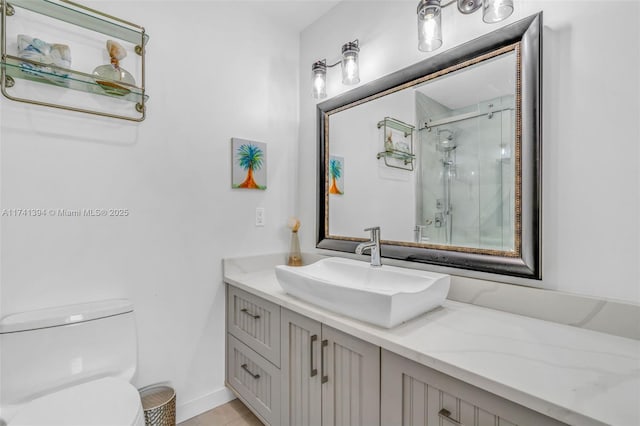 bathroom featuring vanity, a shower with shower door, and toilet